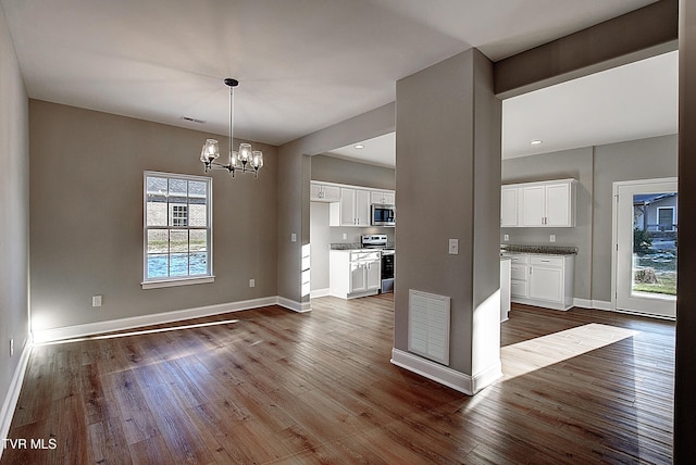 kitchen with stainless steel appliances, a healthy amount of sunlight, white cabinets, and a notable chandelier