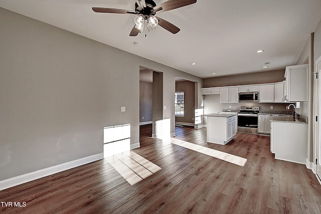 kitchen featuring white cabinets, a kitchen island, stainless steel appliances, light hardwood / wood-style floors, and sink