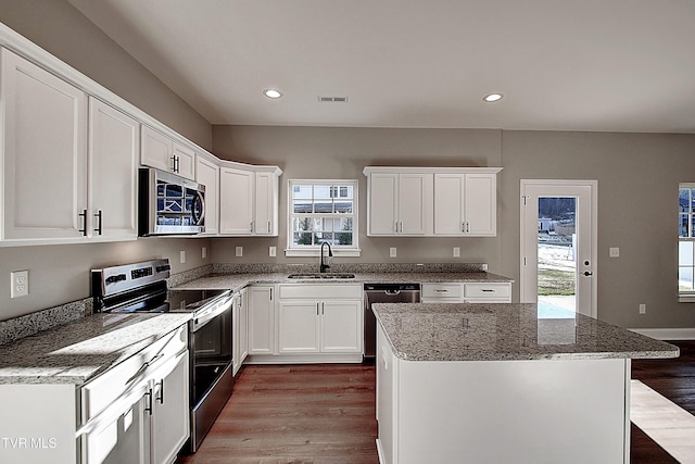 kitchen featuring a center island, sink, white cabinetry, light stone countertops, and appliances with stainless steel finishes