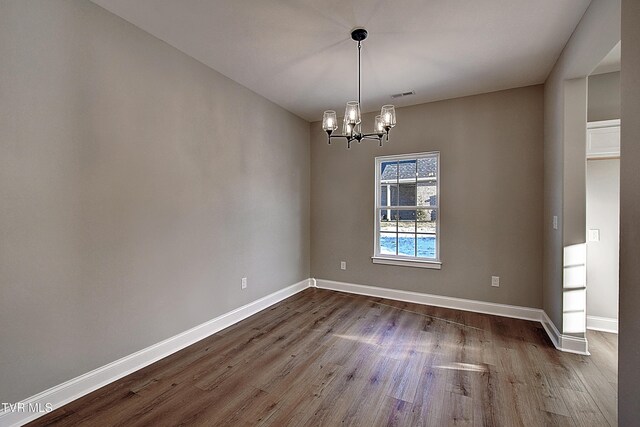 unfurnished room with dark hardwood / wood-style flooring and an inviting chandelier