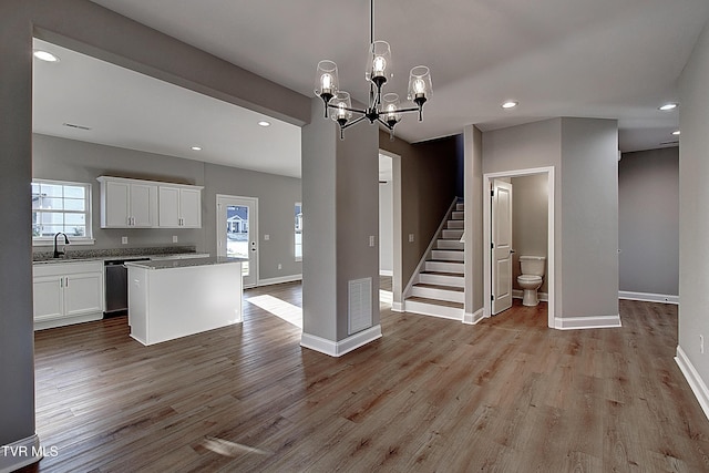 kitchen featuring white cabinetry, sink, hanging light fixtures, stainless steel dishwasher, and a center island