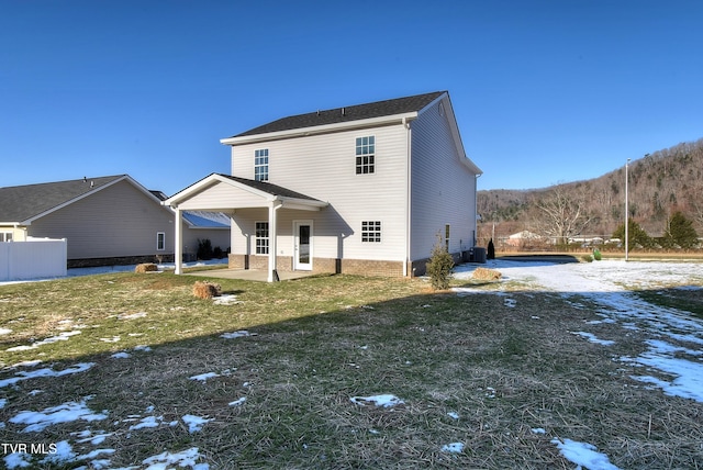 snow covered rear of property featuring a patio area and a lawn