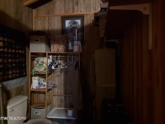 bathroom featuring wood walls and toilet