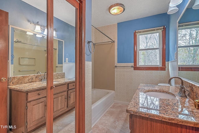 bathroom featuring a textured ceiling, vanity, tile patterned floors, and tile walls