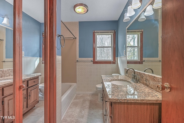 bathroom with tile patterned floors, vanity, toilet, and tile walls