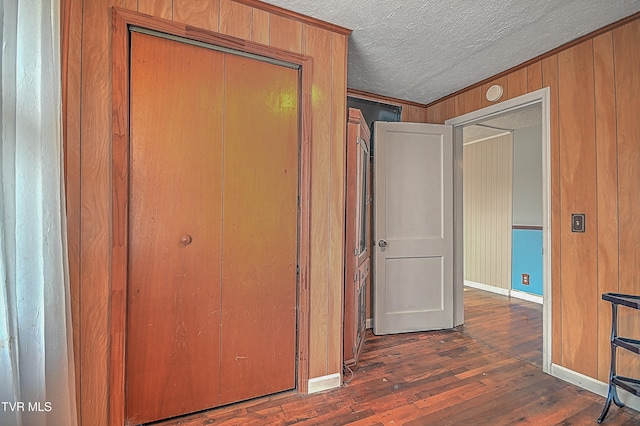 hallway featuring dark hardwood / wood-style flooring, a textured ceiling, and wooden walls