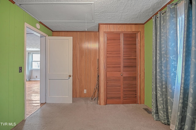 interior space featuring carpet flooring, a textured ceiling, and wooden walls