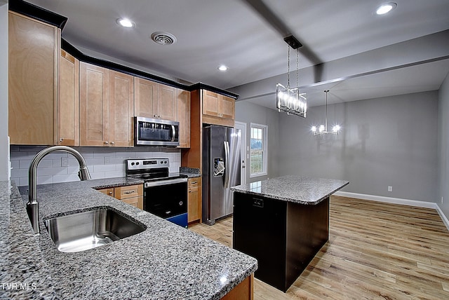 kitchen with pendant lighting, sink, light hardwood / wood-style flooring, a kitchen island, and stainless steel appliances