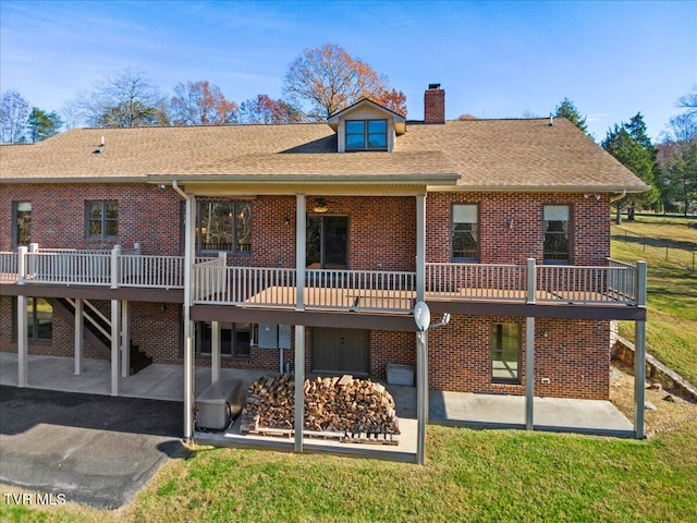 back of property with a lawn, a patio area, and a wooden deck