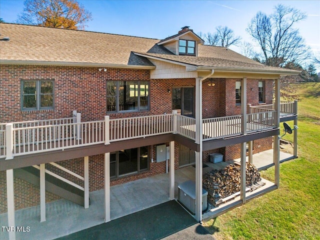 back of house with a wooden deck and a patio