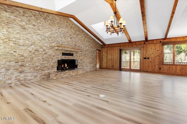 unfurnished living room featuring vaulted ceiling with beams, wood walls, a fireplace, and light wood-type flooring