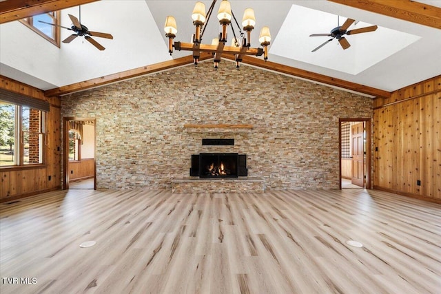 unfurnished living room with beam ceiling, light hardwood / wood-style floors, high vaulted ceiling, and a stone fireplace