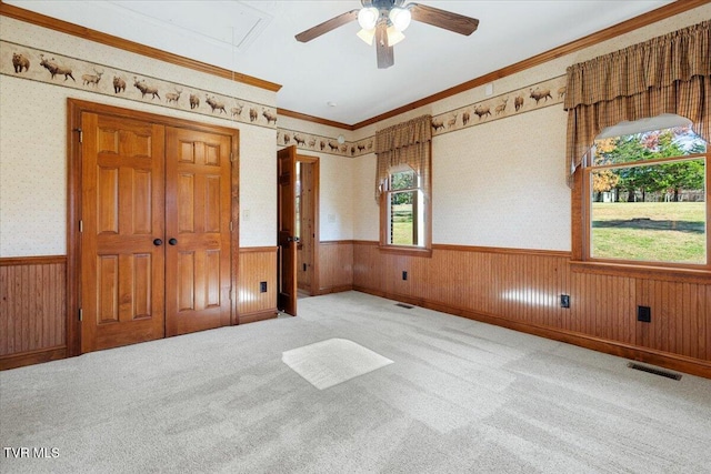 unfurnished bedroom with light carpet, ceiling fan, and wood walls