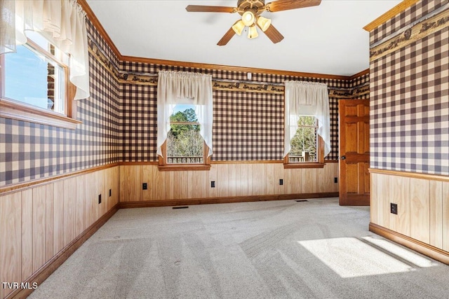 empty room with ceiling fan, light colored carpet, and a wealth of natural light