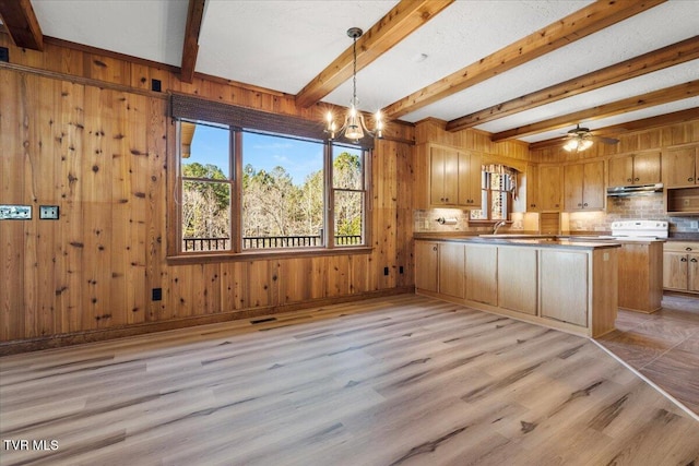 kitchen featuring kitchen peninsula, wood walls, pendant lighting, and light hardwood / wood-style floors