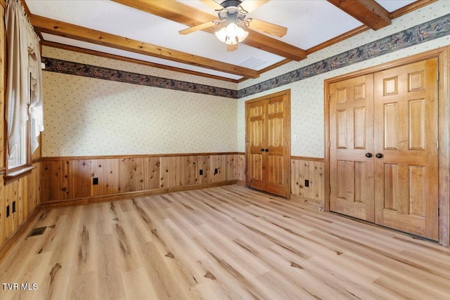 unfurnished bedroom featuring beam ceiling, light hardwood / wood-style flooring, ceiling fan, and wooden walls