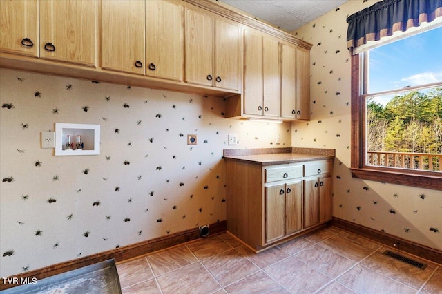 clothes washing area with cabinets and light tile patterned floors