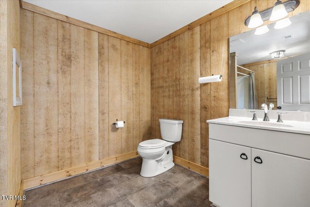 bathroom featuring vanity, toilet, and wooden walls