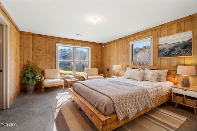 bedroom with visible vents, wooden walls, and concrete flooring