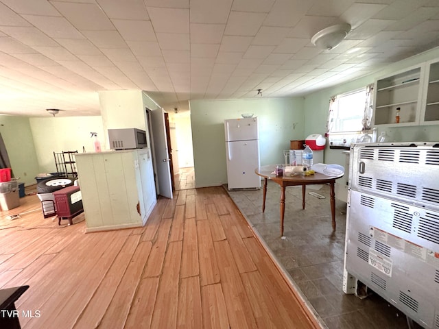 kitchen featuring white cabinets, white fridge, light wood-type flooring, and heating unit