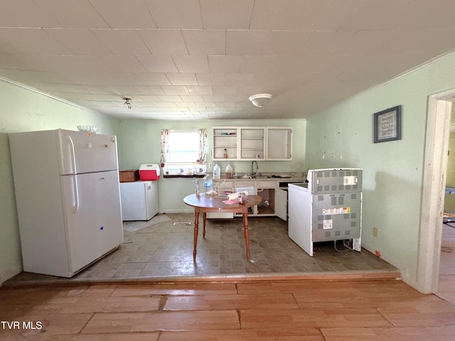 kitchen with white refrigerator, white cabinetry, light hardwood / wood-style flooring, and sink