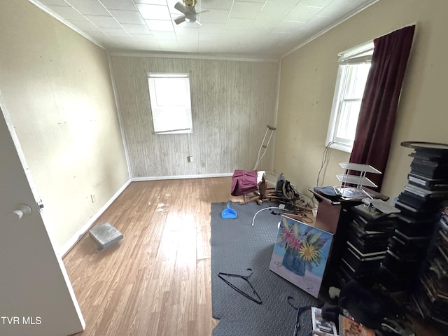 misc room featuring a wealth of natural light, hardwood / wood-style floors, crown molding, and wood walls