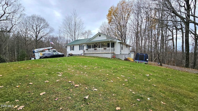 view of front of home with covered porch, a trampoline, and a front lawn