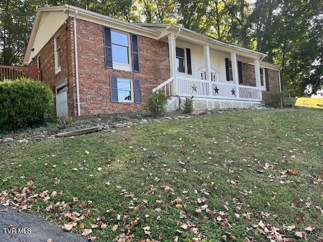 single story home featuring covered porch, a garage, and a front yard