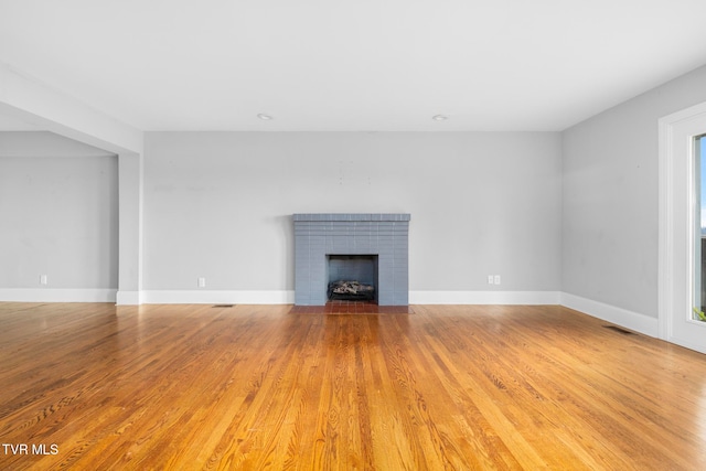 unfurnished living room with a healthy amount of sunlight, light wood-type flooring, and a fireplace