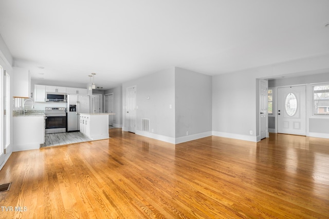 unfurnished living room with light hardwood / wood-style flooring and sink