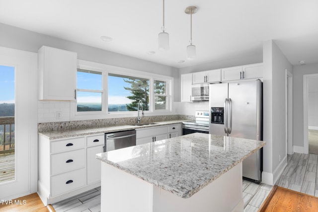 kitchen featuring stainless steel appliances, a kitchen island, decorative light fixtures, white cabinets, and light wood-type flooring