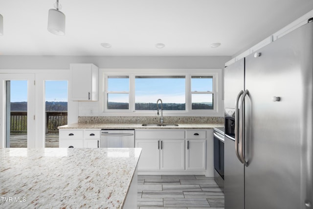 kitchen featuring decorative light fixtures, white cabinetry, sink, and appliances with stainless steel finishes