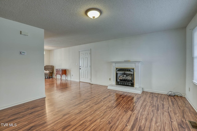 unfurnished living room featuring a textured ceiling and dark hardwood / wood-style floors