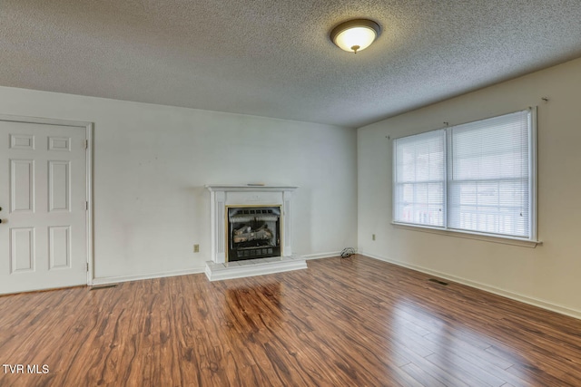 unfurnished living room with a textured ceiling and dark wood-type flooring