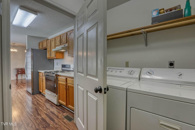 clothes washing area featuring dark hardwood / wood-style flooring, a chandelier, a textured ceiling, and independent washer and dryer