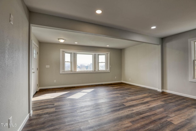 spare room featuring dark wood-style floors and baseboards