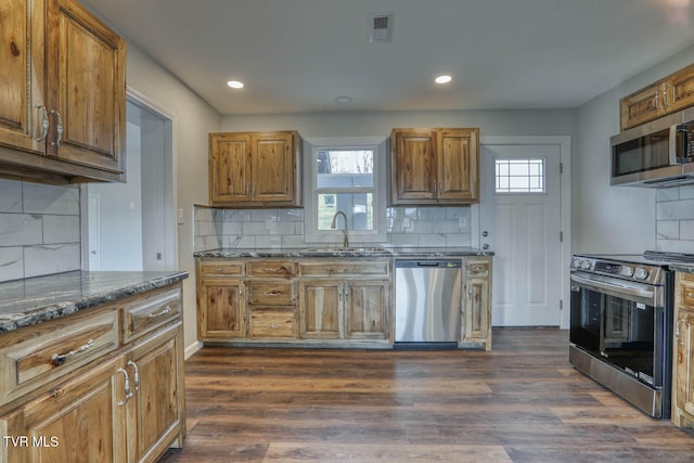 kitchen with a wealth of natural light, appliances with stainless steel finishes, dark wood finished floors, and a sink