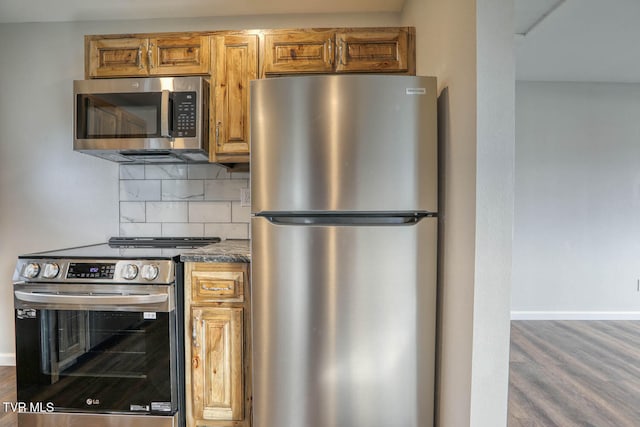 kitchen with stainless steel appliances, wood finished floors, baseboards, tasteful backsplash, and dark countertops