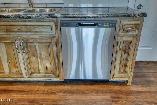 interior details featuring dark countertops, dark wood finished floors, a sink, and stainless steel dishwasher