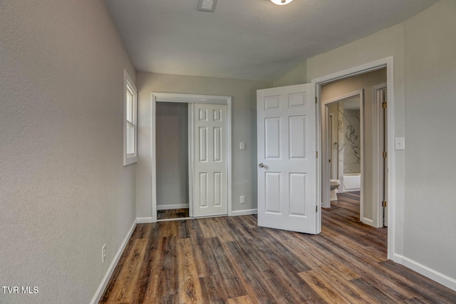 unfurnished bedroom with dark wood-style floors, a closet, and baseboards