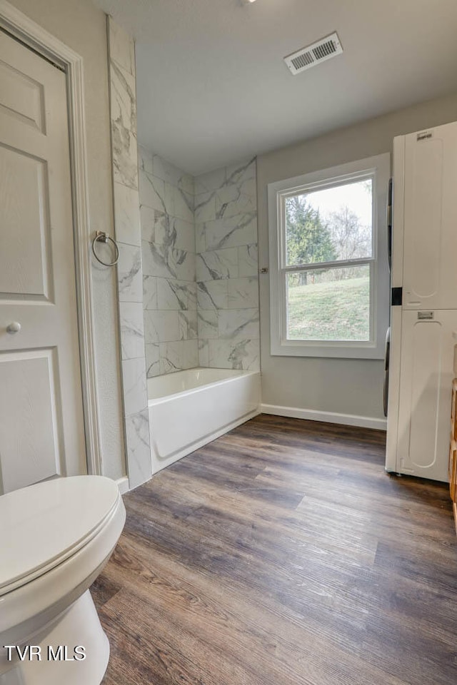 bathroom with baseboards, visible vents, toilet, and wood finished floors