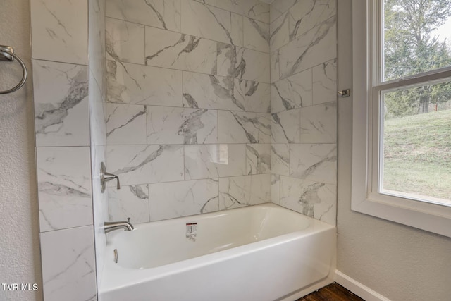 full bathroom featuring plenty of natural light, baseboards, shower / bathing tub combination, and a textured wall