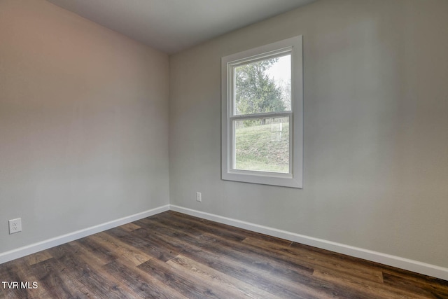 empty room with baseboards and dark wood-type flooring