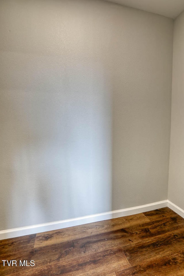 spare room featuring dark wood finished floors and baseboards