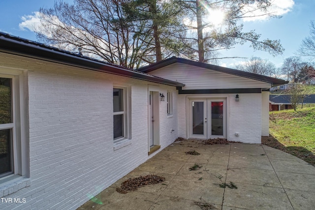 rear view of property featuring brick siding, french doors, and a patio