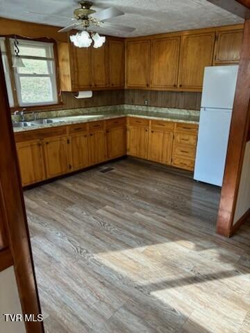 kitchen with ceiling fan, sink, white fridge, light hardwood / wood-style floors, and a textured ceiling