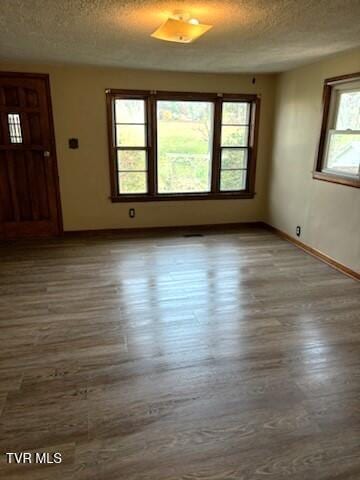 empty room with dark hardwood / wood-style flooring and a textured ceiling