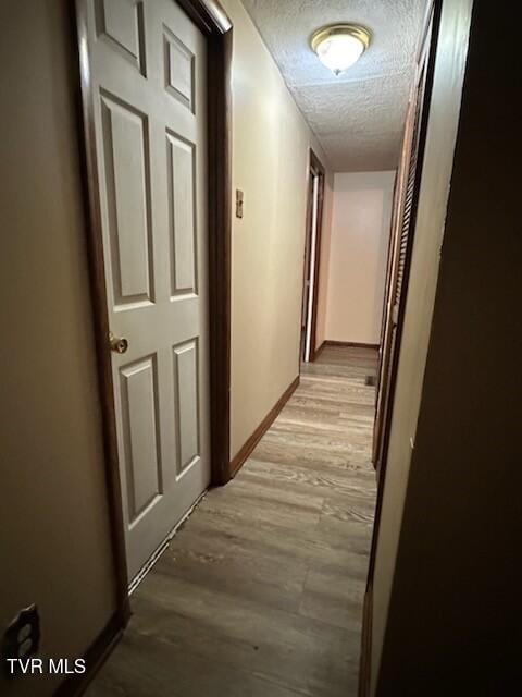 corridor with light hardwood / wood-style floors and a textured ceiling