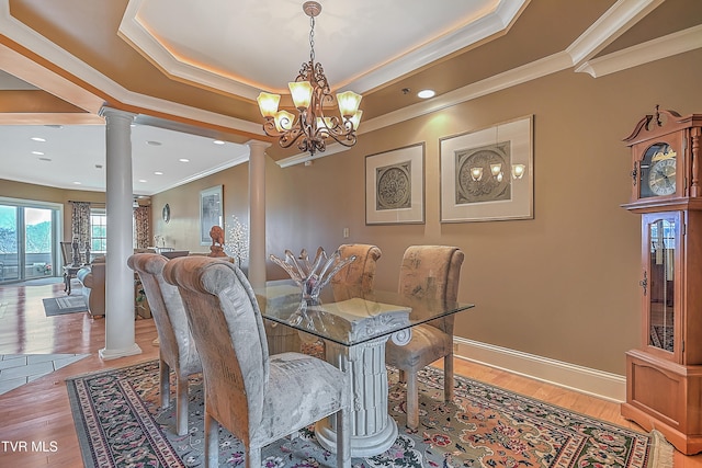 dining area with decorative columns, crown molding, a chandelier, and hardwood / wood-style flooring