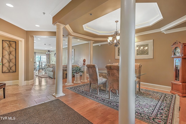 dining room with hardwood / wood-style flooring, ornate columns, crown molding, and a chandelier